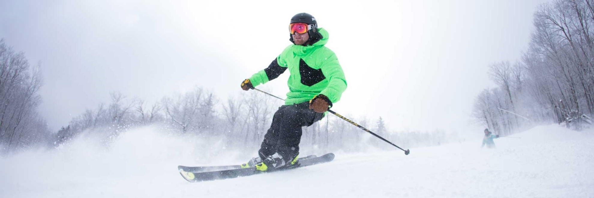 skier in green jacket skiing down a trail